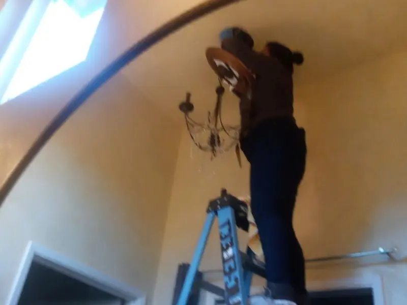 Electrician installing a chandelier in a White City residence